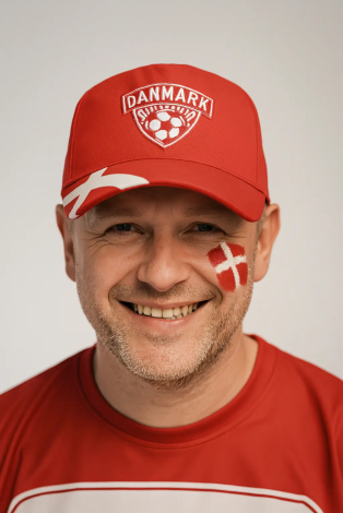 Mandlig fodboldfan med rød Danmark kasket og Dannebrog malet på kinden smiler