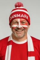 Glad dansk fodboldfan med Danmarks flag malet i ansigtet og Dannebrog hue