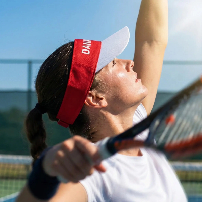 Kvinde spiller tennis med en rød og hvid tennis kasket med 