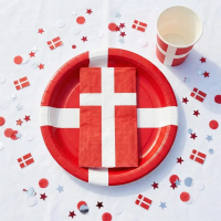 Opdækket bord med Dannebrog festpakken, som består af papkrus, servietter og tallerkner i rød og hvid