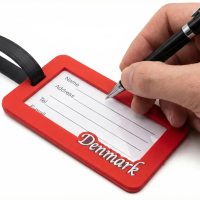 Nærbillede af bagsiden på kuffertmærket, hvor en hånd holder en kuglepen klar til at udfylde adressefeltet