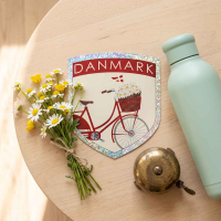 Klistermærke med cykel og blomster motiv ligger på et dekoreret bord