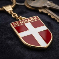 Nærbillede af Dannebrog nøglering i metal med rød og hvid emalje og DENMARK øverst på skjoldet